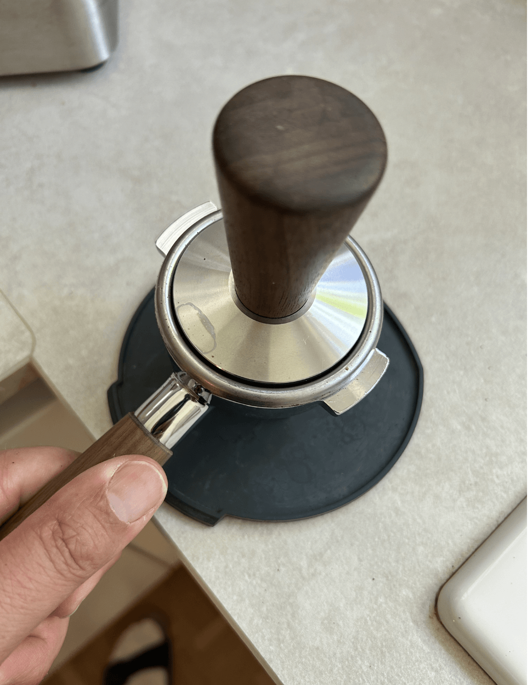 Kaffeemehl wird mit dem Holz-Tamper gerade und gleichmäßig getampert 
