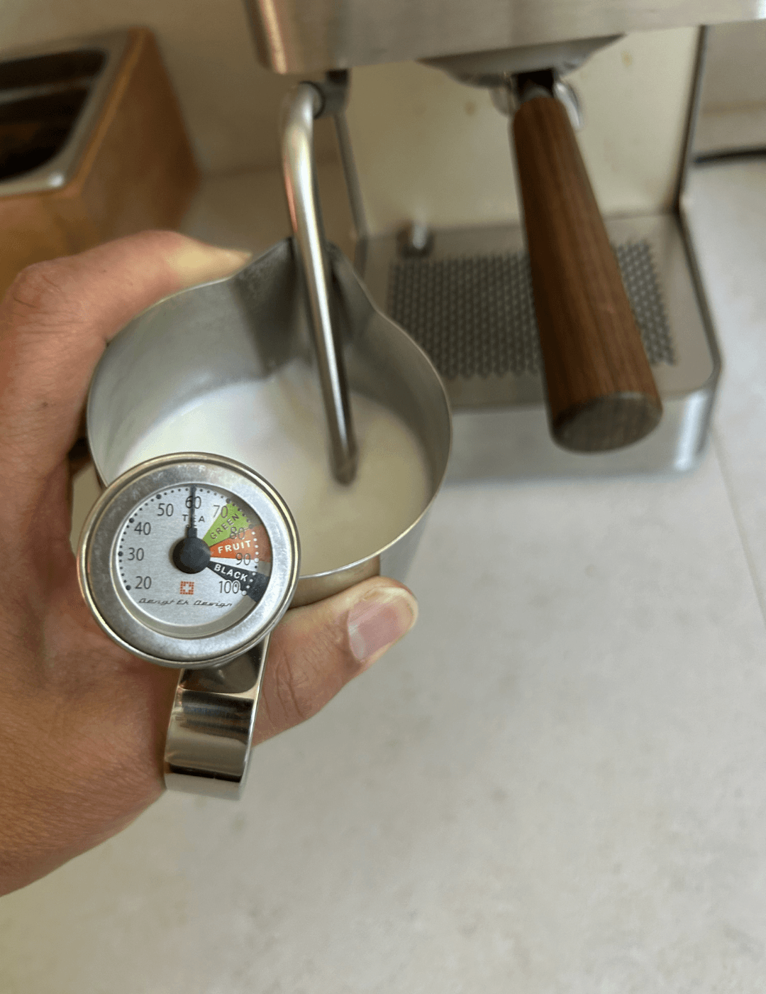 Milchtemperatur wird mit einem Thermometer am Kännchen auf 60 bis 65 Grad kontrolliert