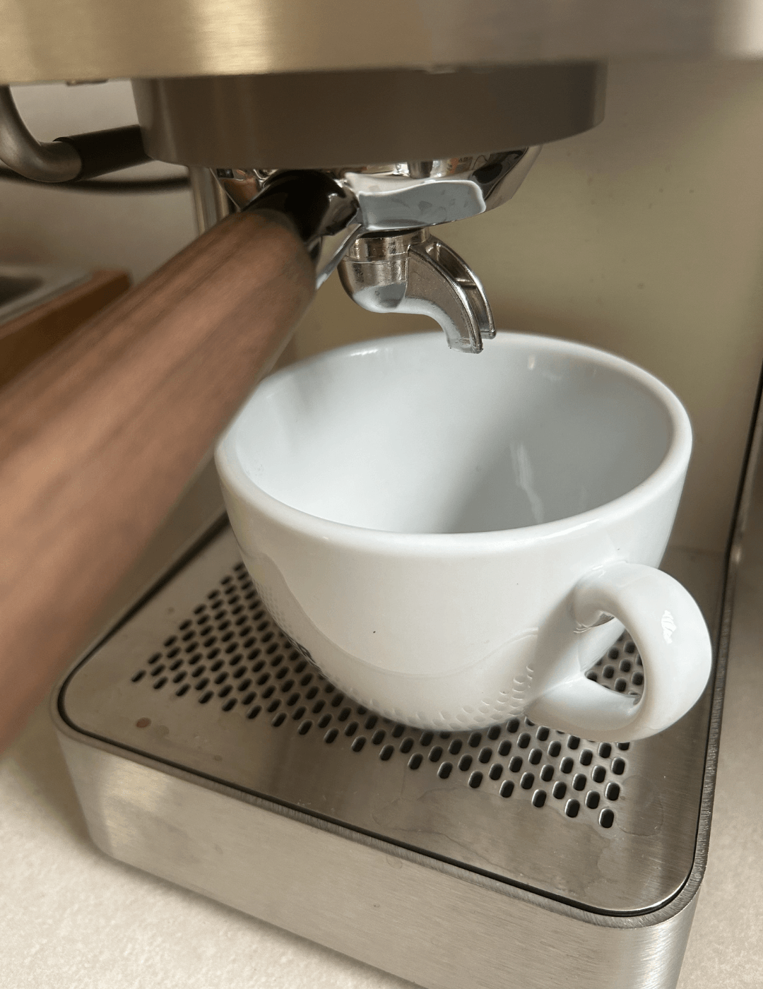 Zuriga E2-2 mit Walnussgriff-Siebträger brüht Espresso in eine weiße Tasse