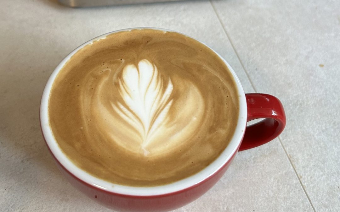 Flat White mit flachem Mikroschaum und Rosetta-Latte-Art in einer roten Tasse