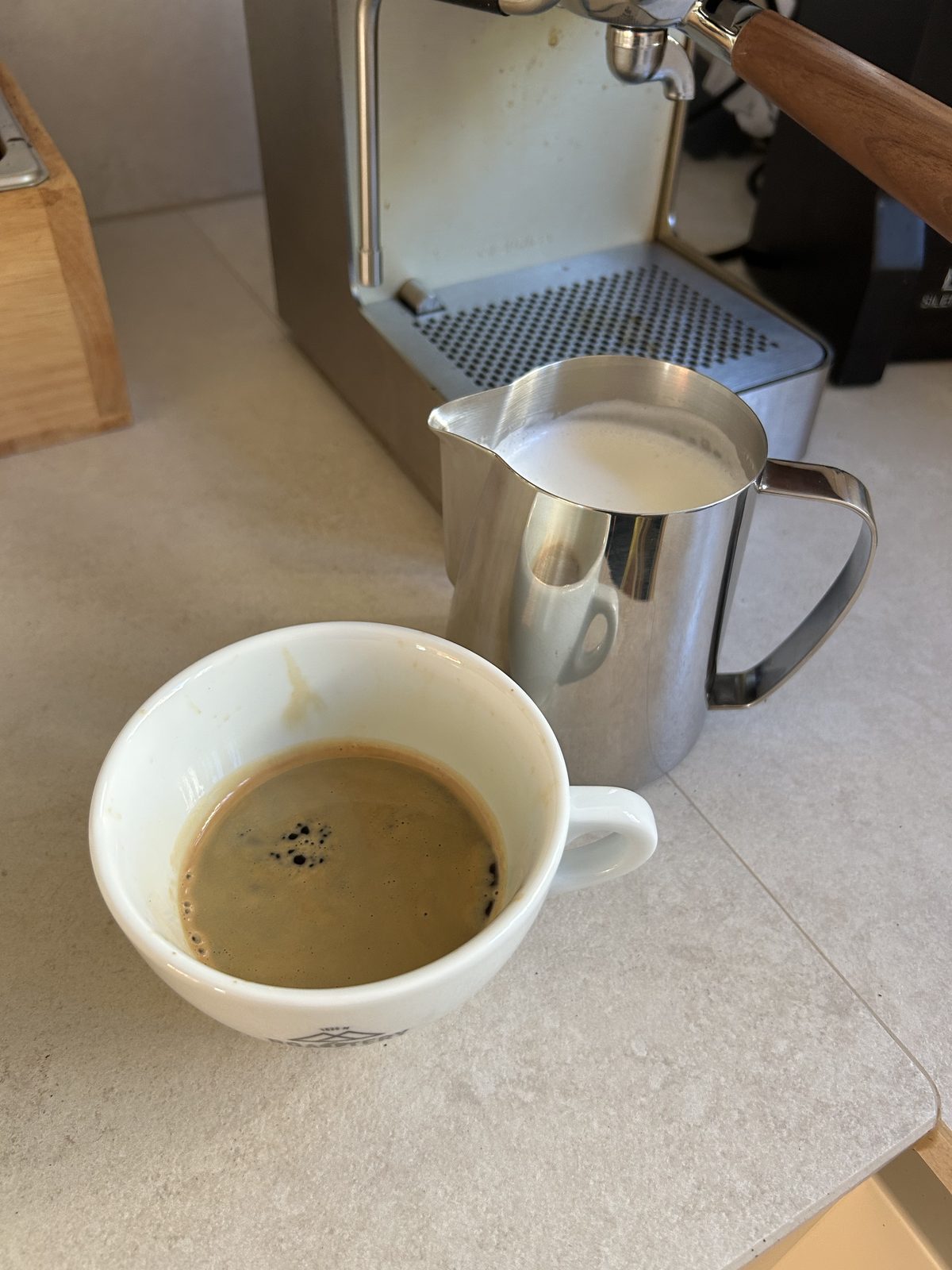 Doppelter Espresso auf dem Sirup, daneben das Kännchen mit aufgeschäumter Milch