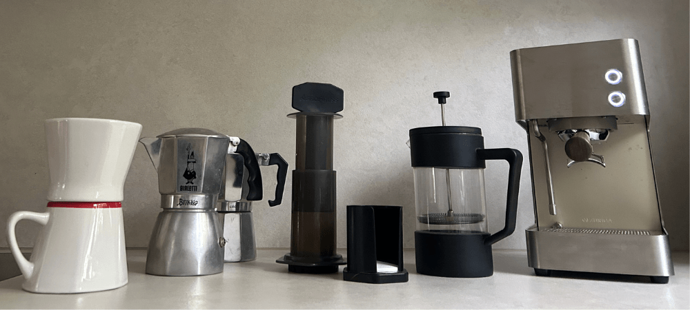 schwarzer-kaffee-fuenf-zubereitungen Fünf Zubereitungen für schwarzen Kaffee nebeneinander: Handfilter, Espressokocher, AeroPress, French Press und Siebträgermaschine