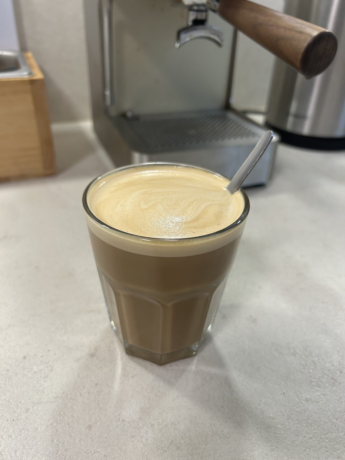 Americano mit geschäumter Milch im Glas vor der Siebträgermaschine