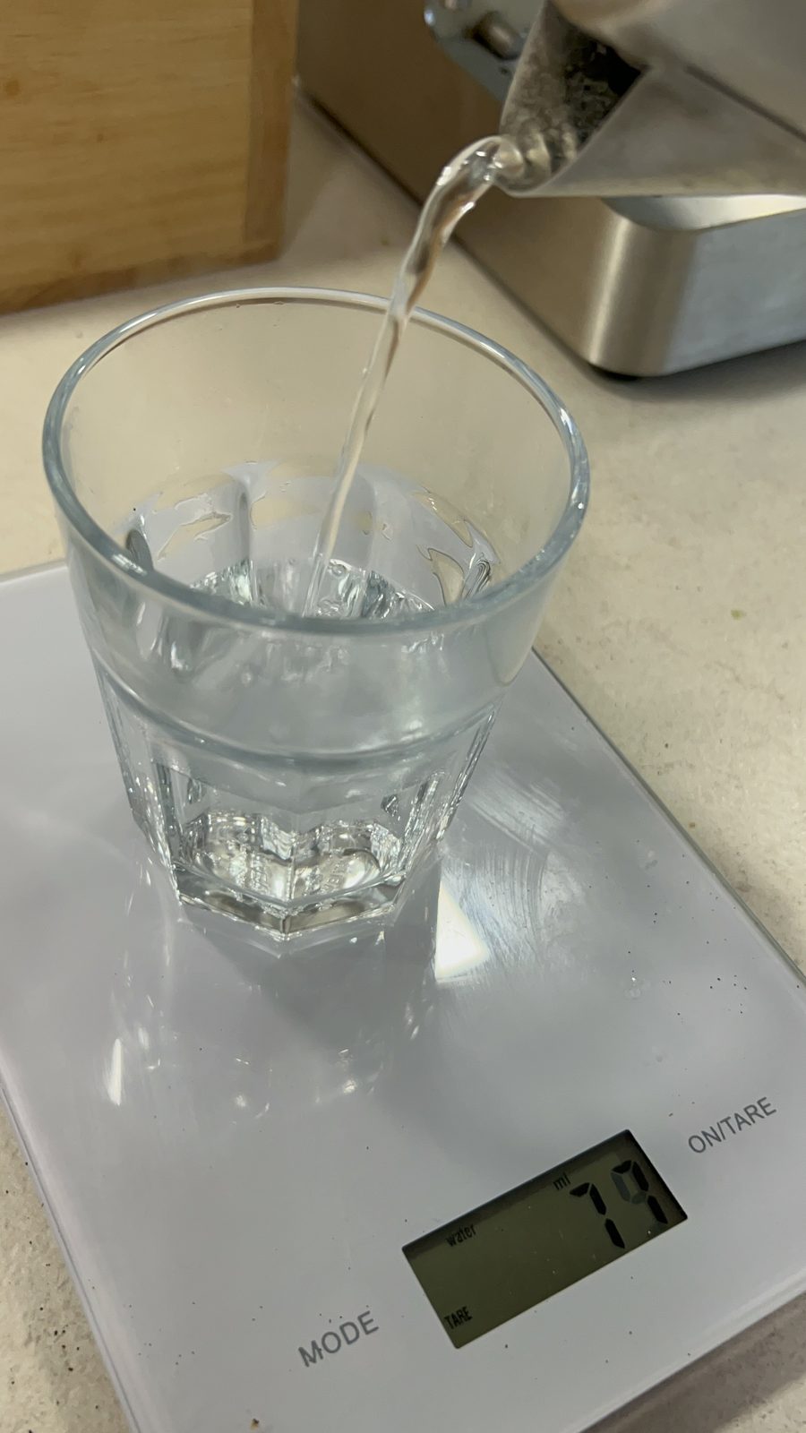 Heißes Wasser wird für einen Long Black in ein Glas auf der Küchenwaage gegossen